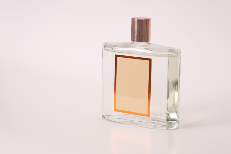 A clear perfume bottle with an empty label, suitable for branding or design purposes.