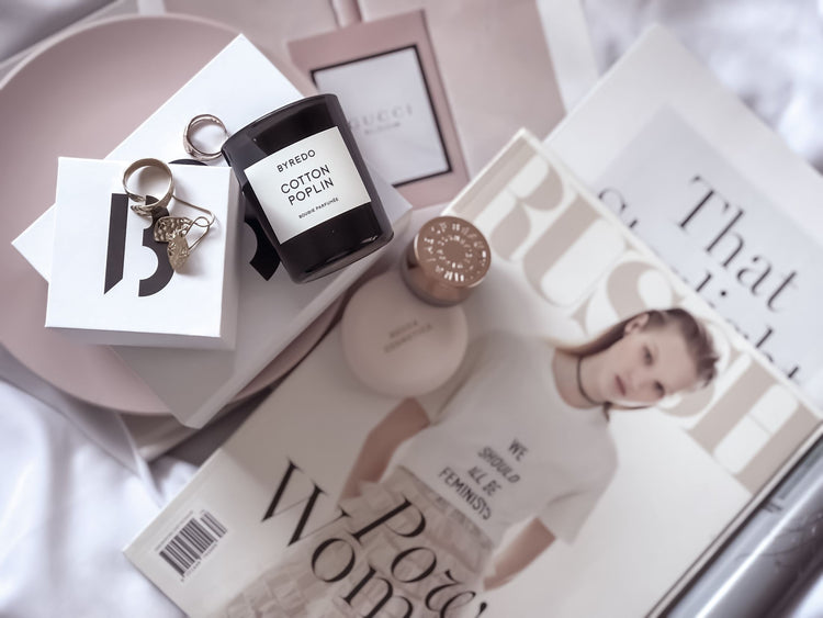 Stylish flat lay featuring fashion magazines, Byredo candle, and accessories.